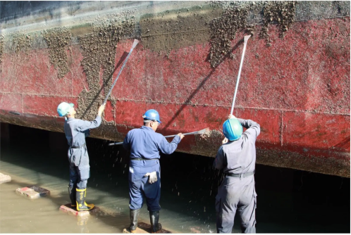 Workers are using shovels to clean the corroded coating on the ship