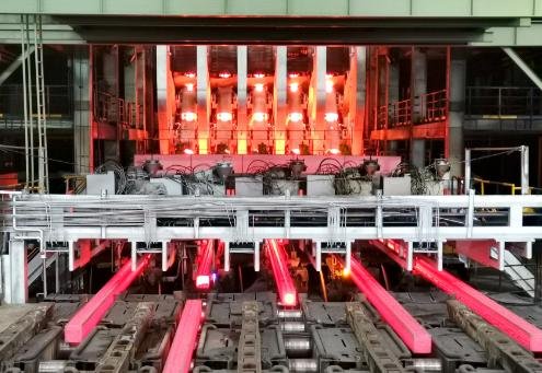 High temperature resistant coating - Quartzmaster Industrial forging plant with glowing red-hot metal bars traveling on a conveyor under steel framework